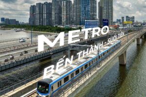 Hình ảnh tàu metro đang chạy trên cầu, với phông nền là các tòa nhà cao tầng và dòng sông, có chữ 'Metro Bến Thành - Suối Tiên' nổi bật